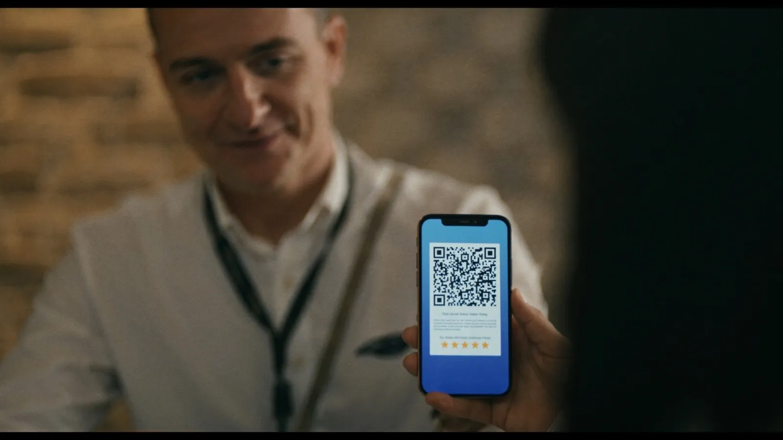 Verslo savininkas rodo klientui QR kodą telefone, kad paliktų Google atsiliepimą