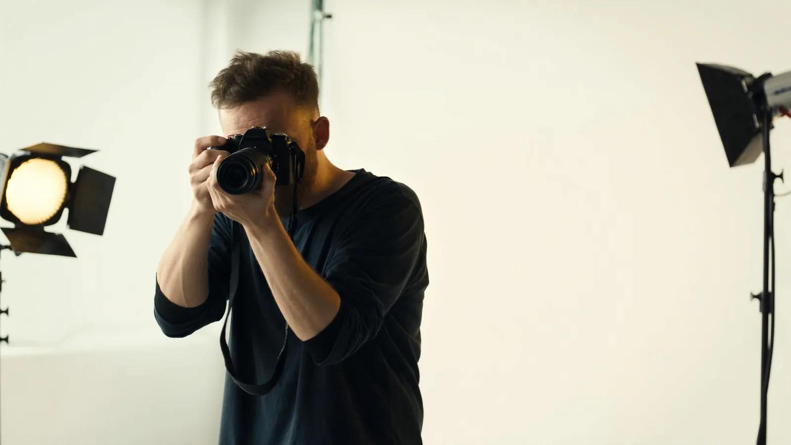 Profesionalus fotografas šviesioje modernioje studijoje su fotoaparatu, softbox apšvietimas ir fonas