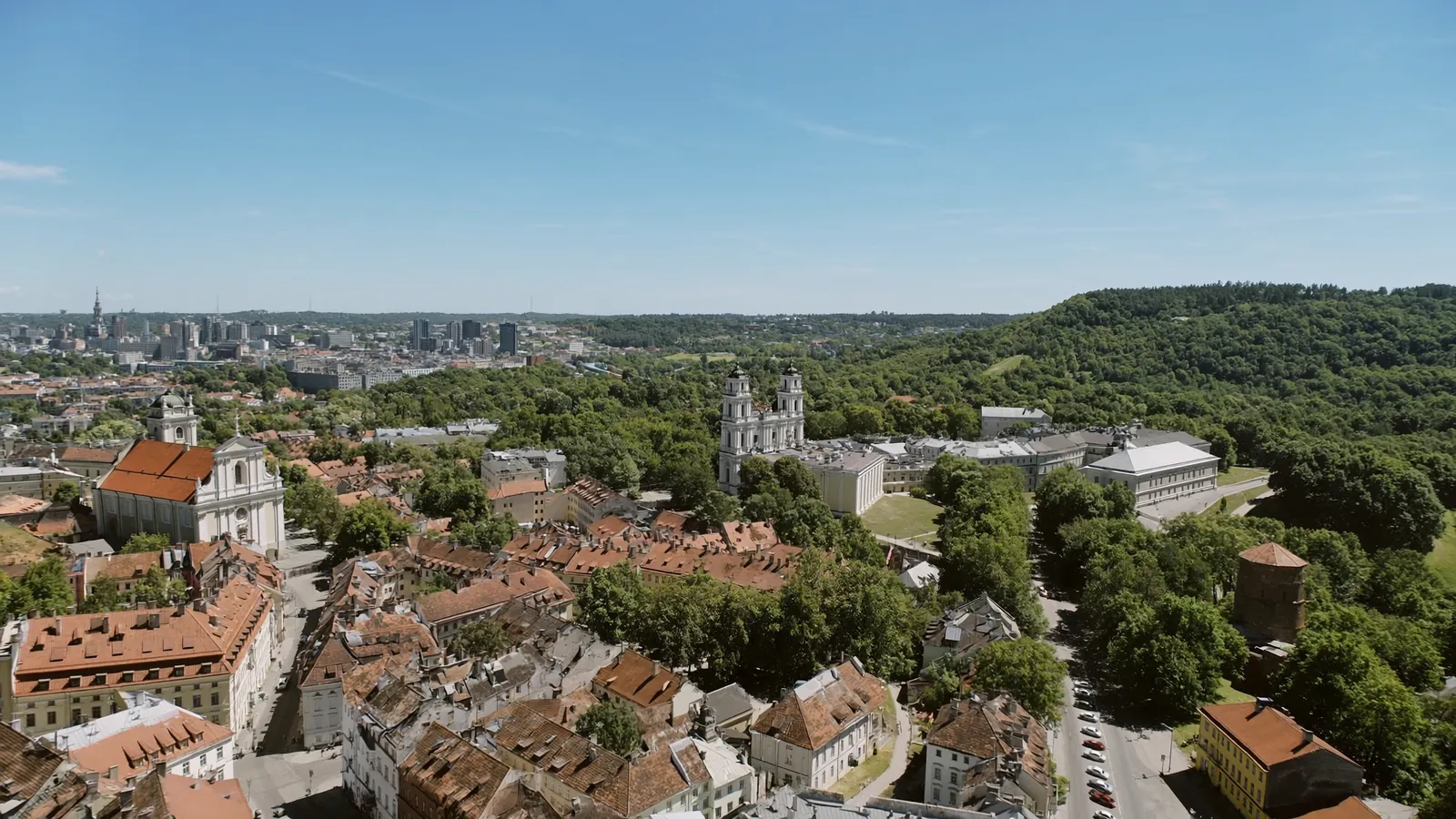 Šviesus Vilniaus senamiesčio vaizdas iš viršaus su raudonais stogais ir bažnyčių bokštais saulėtą dieną
